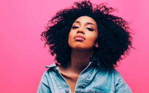 Mulher negra representando o outubro rosa, com um fundo rosa